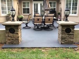 Twin half columns made from polyurethane stone flank the entrance of an outdoor patio.