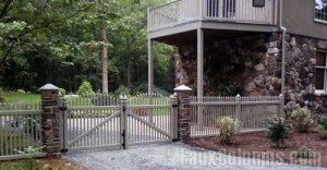 Stone style driveway entry columns attached to a wooden fence
