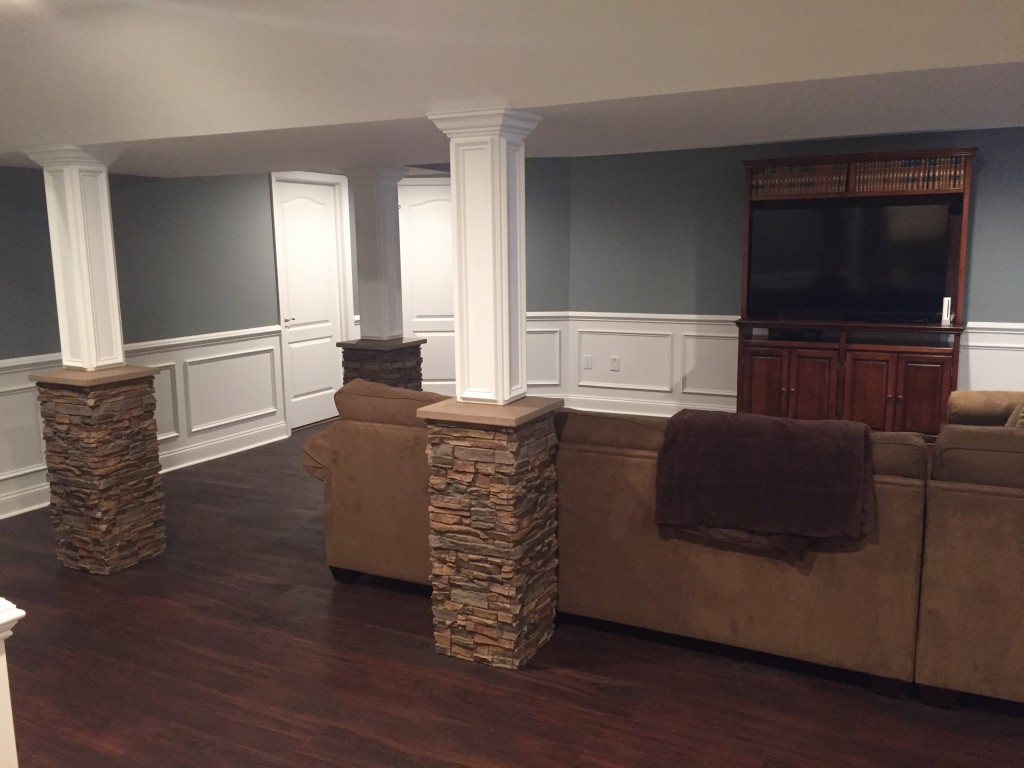 Finished basement with support columns enhanced with fake stone column wraps