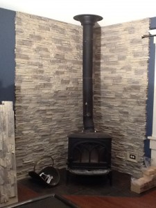 Wood stove backing built with stacked stone style, fire-rated panels