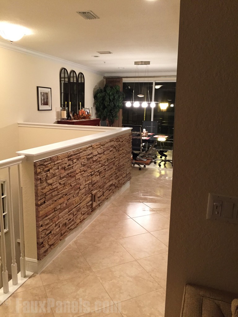 Half wall at the top of a home's stairway clad in drystack panels.