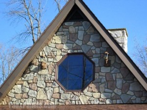 Home exterior with octagonal front window outfitted with faux fieldstone panels.
