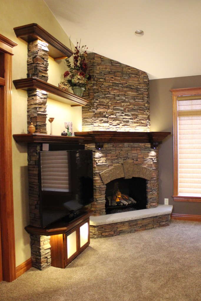 Fireplace build complete with stacked stone finish and wooden shelving.