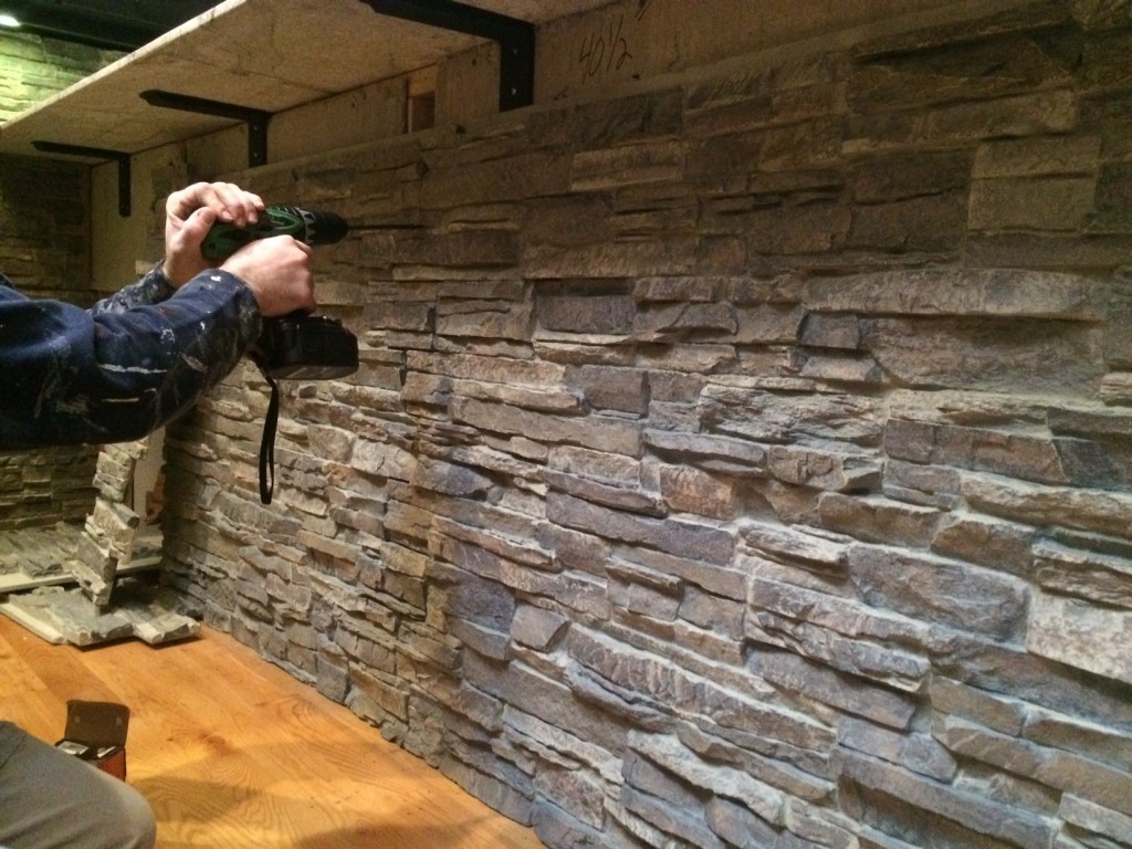 Stone look panels being screwed onto a kitchen island's wooden frame.