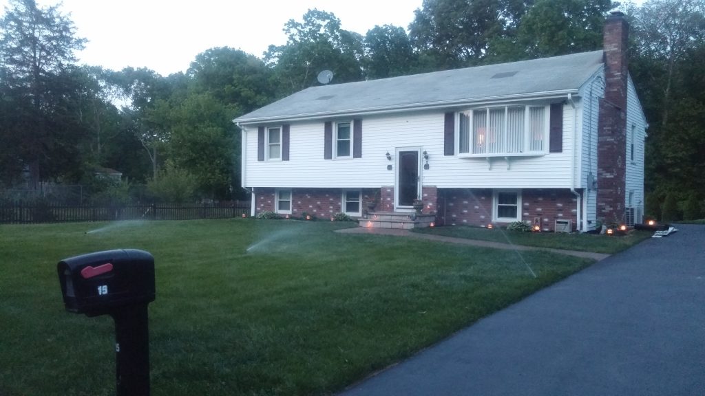 Split level ranch with white vinyl siding and brick accent siding on the foundation and chimney.