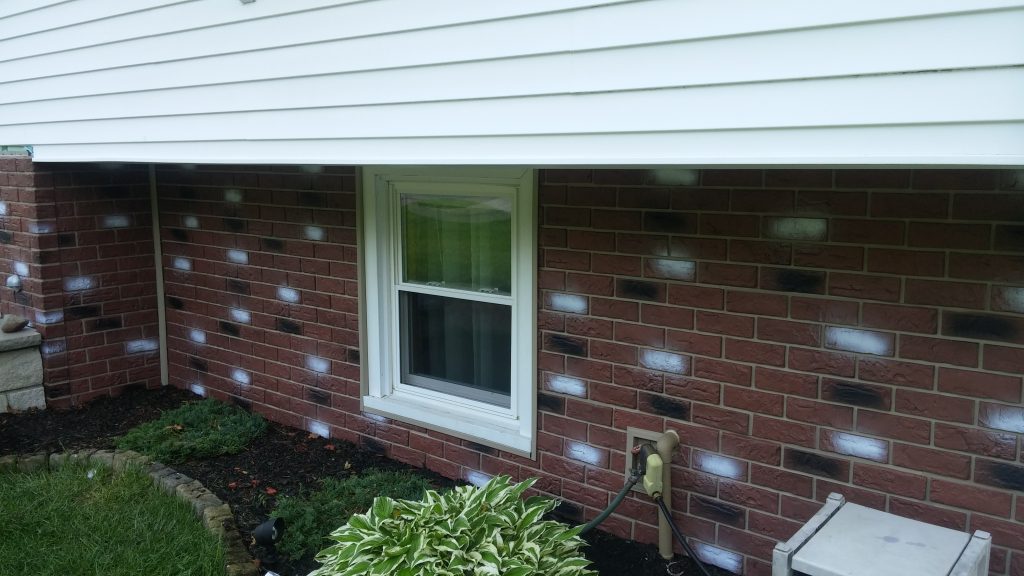Close up view of faux brick exterior siding installed on a home's foundation