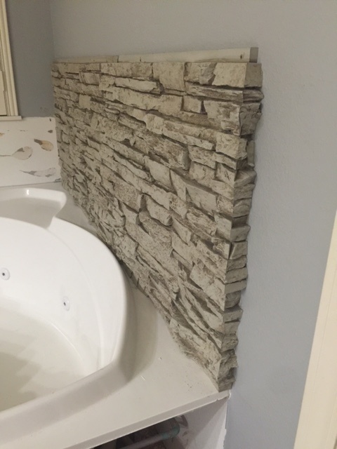 Beginning installation of waterproof wall panels around a corner bathtub