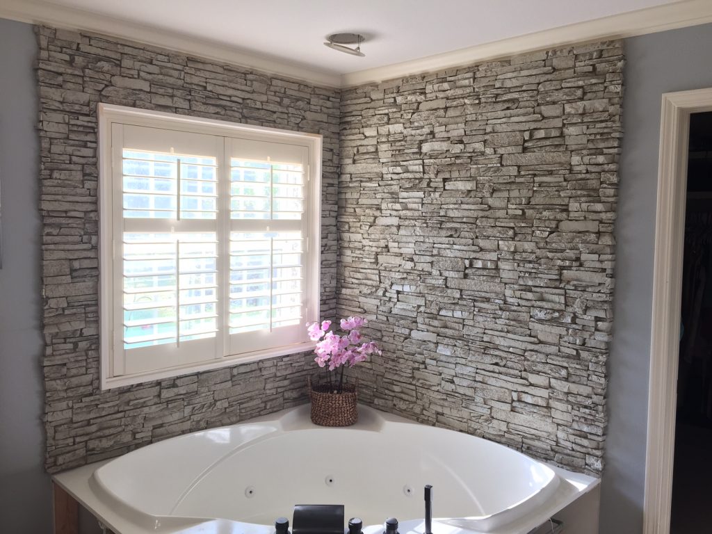 Luxury corner bathtub with a backsplash surround with the look of real stacked stone.