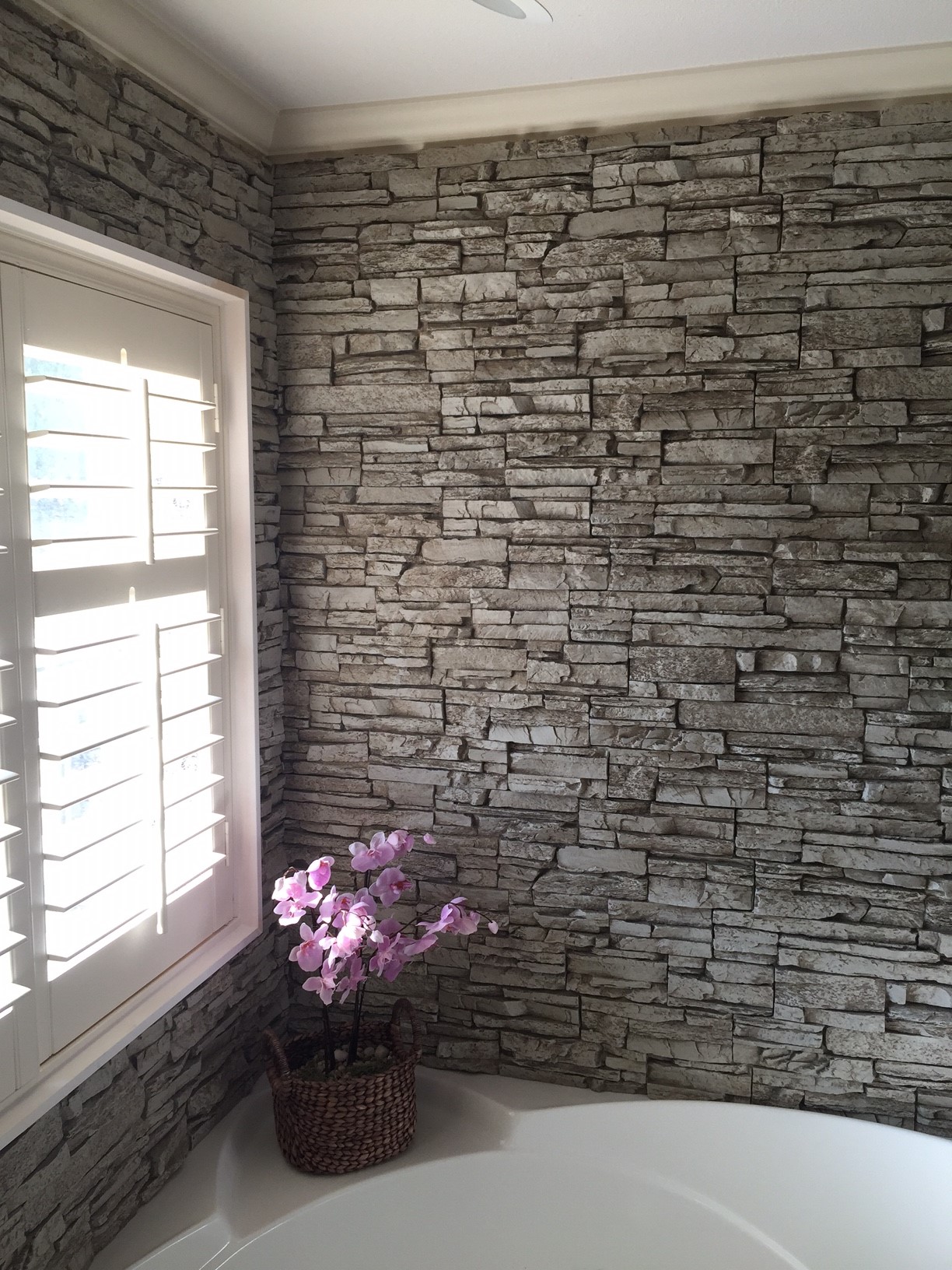 Gorgeous bathtub wall surround created with Norwich Stacked Stone panels in a light gray color.