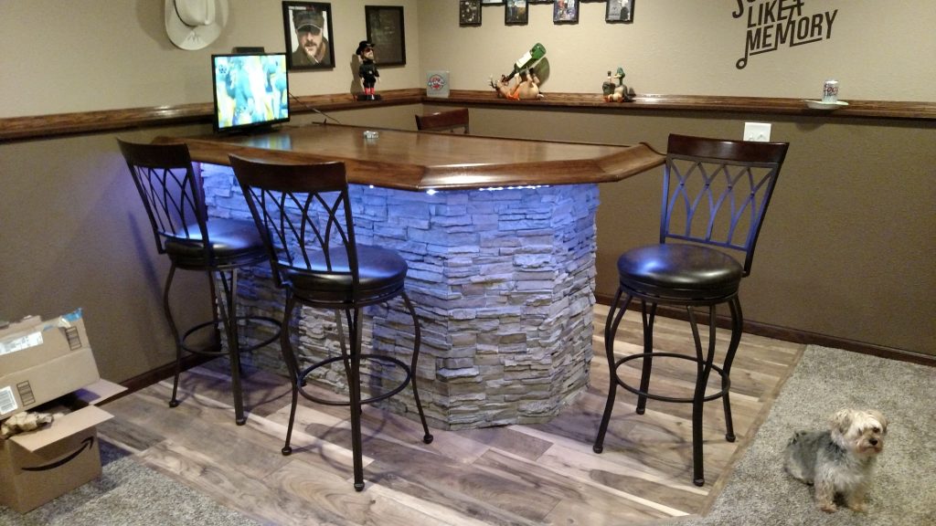 A home bar's based covered in new stacked stone veneer with LED lights installed underneath the bar top