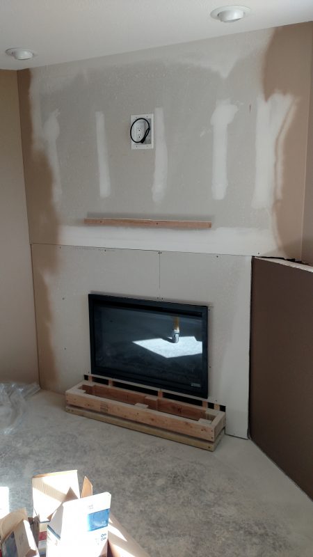 BEFORE: The fireplace is made from regular framing and drywall; and Tanner installed the panels directly onto the surface of the new wall.
