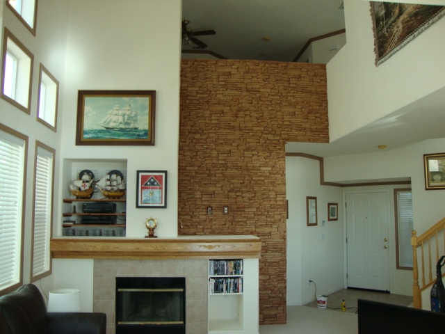 Completed fireplace wall clad in stacked stone style panels.
