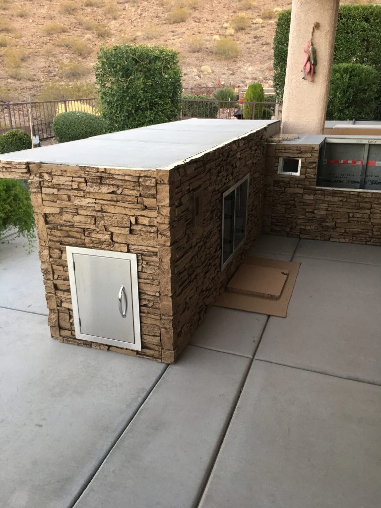 DIY BBQ island covered in stacked stone style panels and corners for a seamless, realistic look.