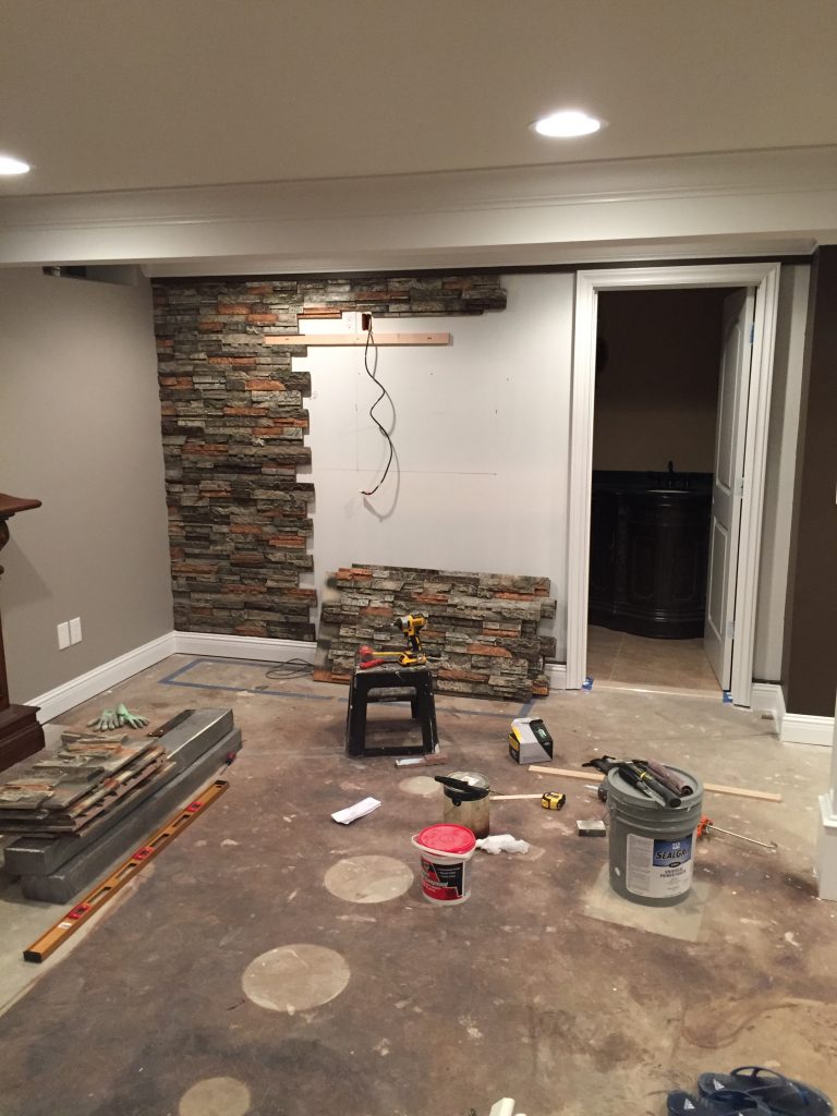 Adding panels that fit together like a jigsaw puzzle on a finished basement's wall.