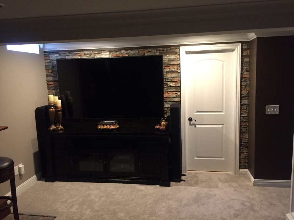 Finished basement. With the TV and furniture in place, it's impossible to tell the wall isn't really stone.