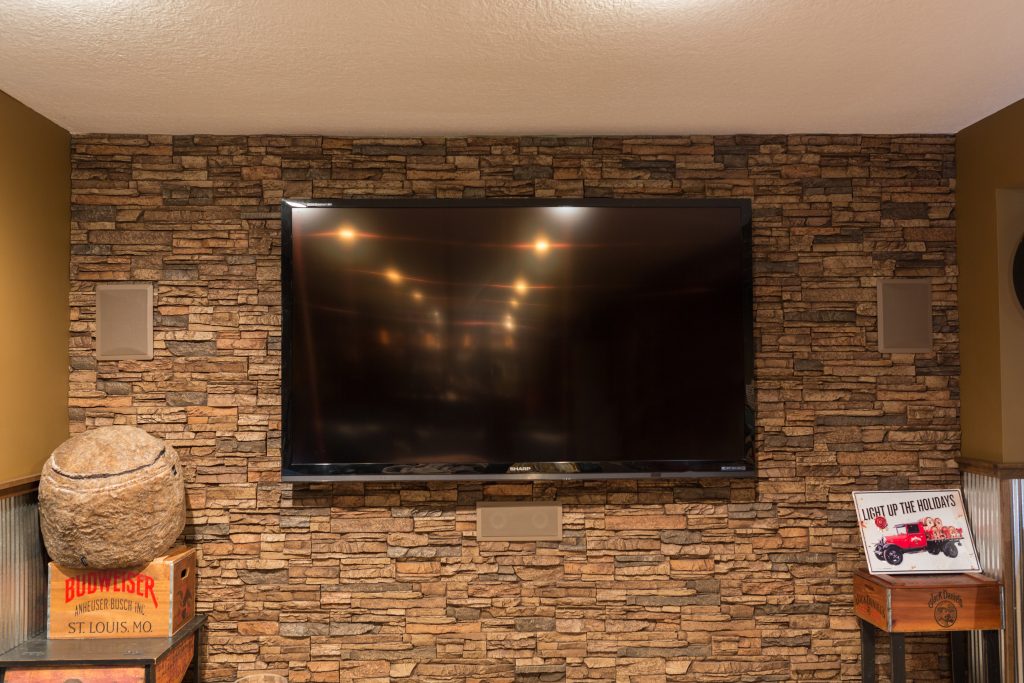 A basement' TV wall covered in Norwich Stacked Stone panels in Sierra Brown color.