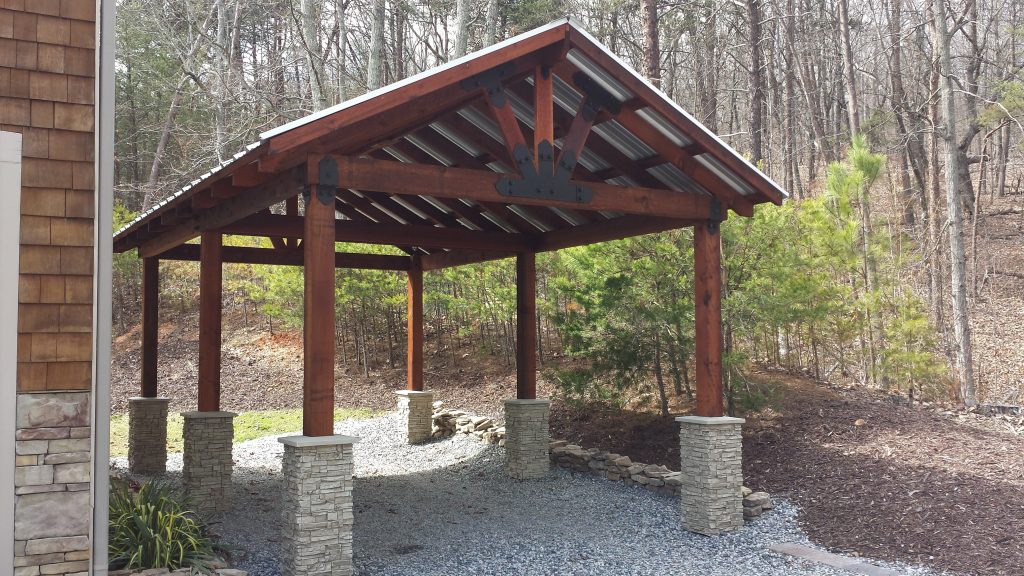 Timber carport design with stacked stone column wraps installed around the base of each supporting post.
