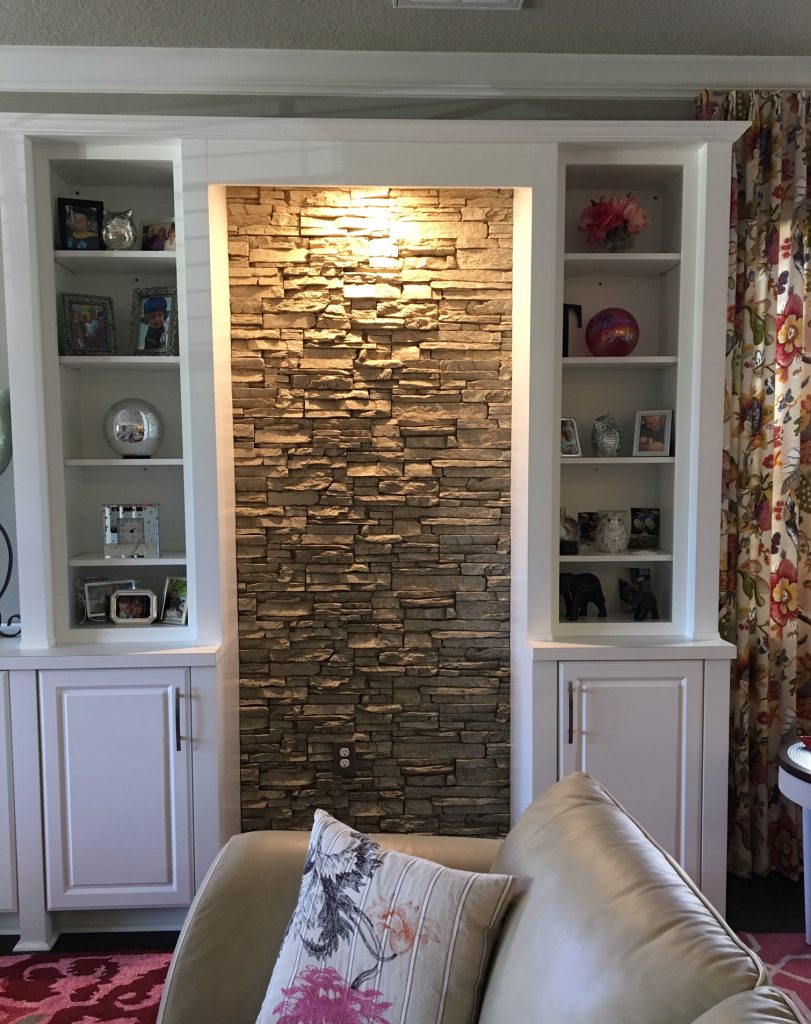 Shelving unit design enhanced with a simple stacked stone accent wall.