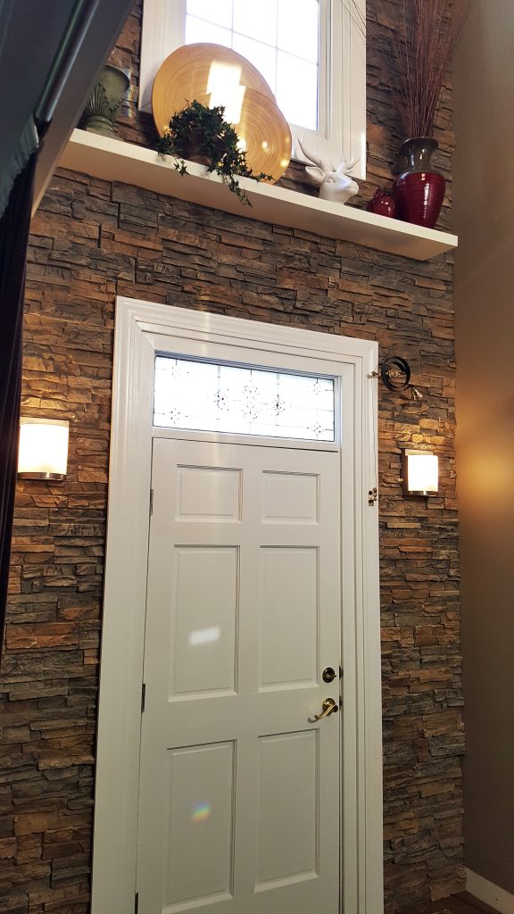 Close up view of a home's doorway surrounded with stacked stone style panels.
