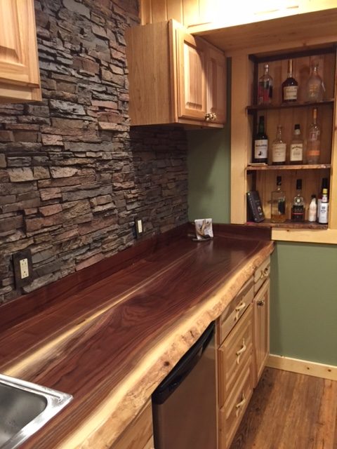 Close-up view of a kitchen backsplash created with stacked stone style panels and matching outlet covers.