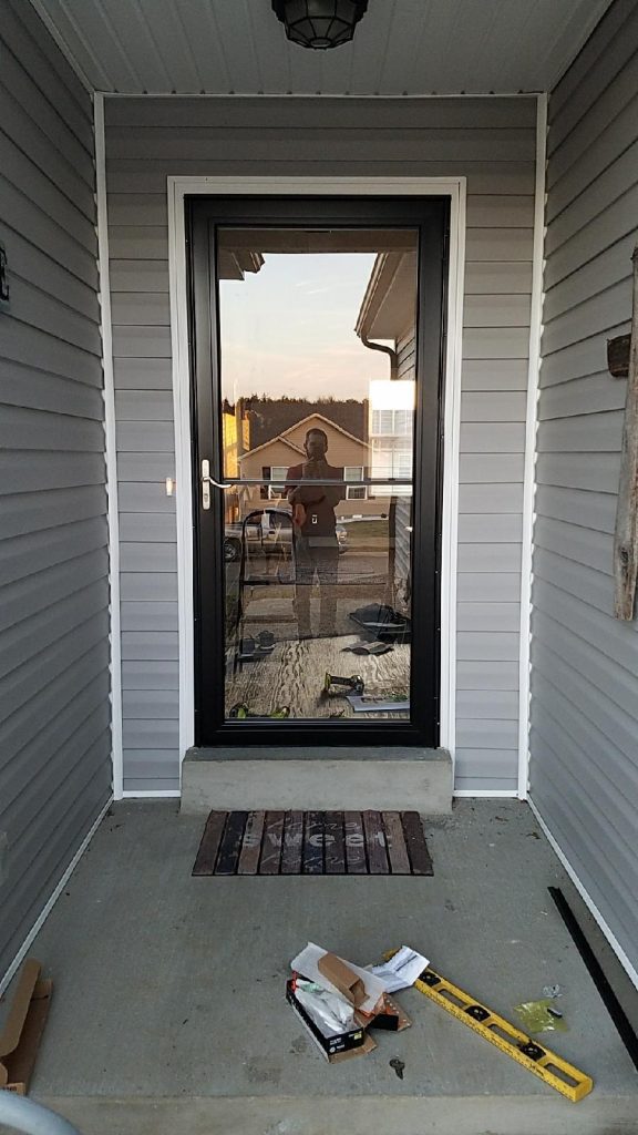 The original doorway with surrounded by grey vinyl siding 