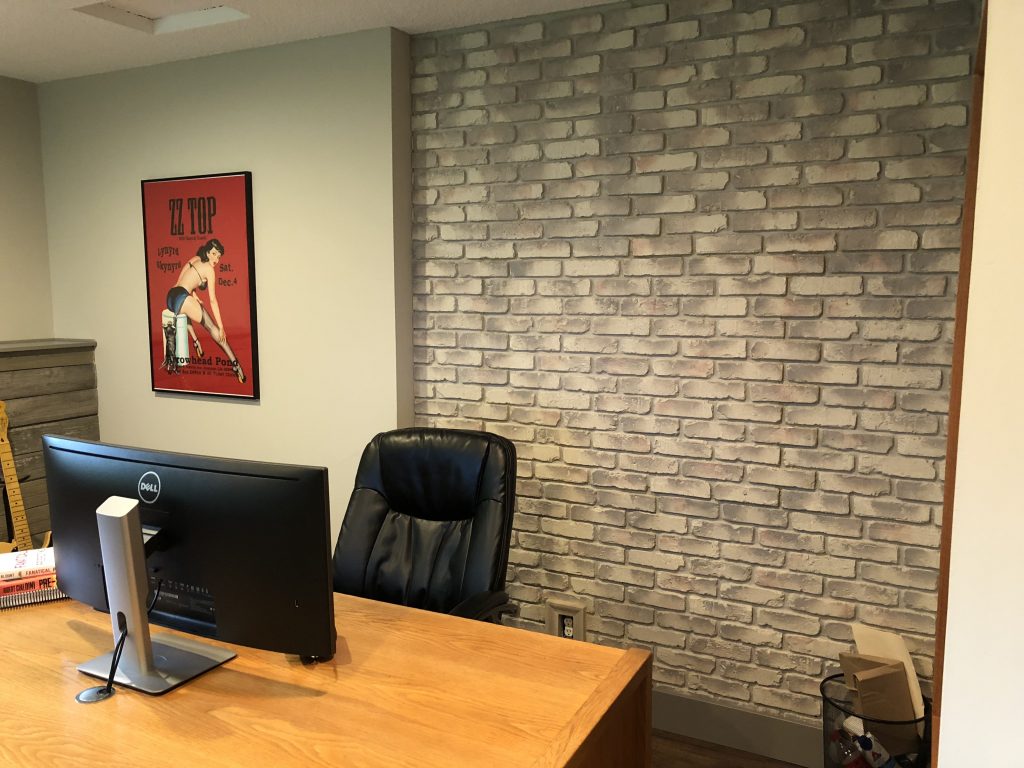 A faux brick panel accent wall behind a desk in an office