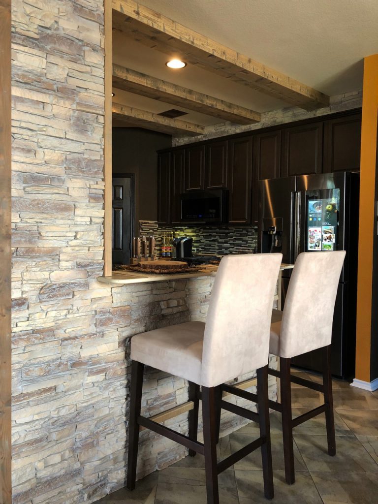 Kitchen with Hand Hewn real wood beams on the ceiling and Norwich Stacked Stone panels on the bar.