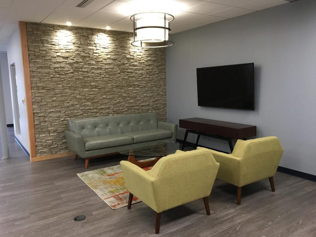 Law office waiting room renovated with a new stacked stone style accent wall in creamy beige.
