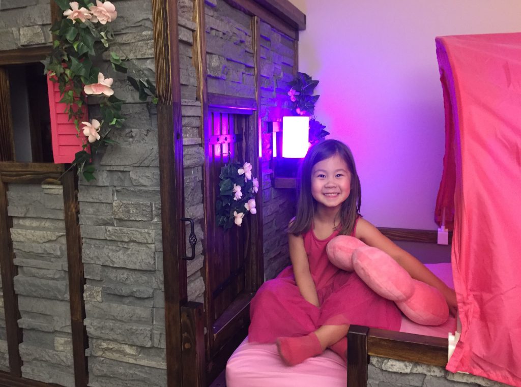 4 year old girl posing with her new princess castle bed built by her Dad.