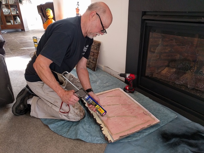 Applying construction adhesive to the back of a panel.