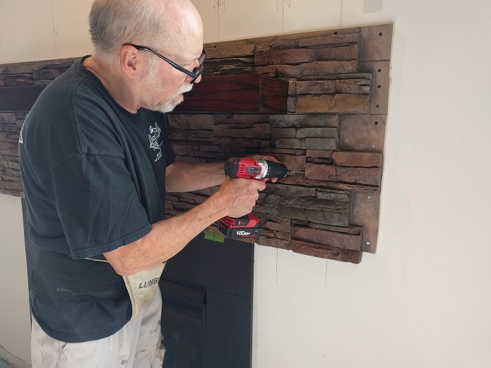 Securing panels around a fireplace with screws.