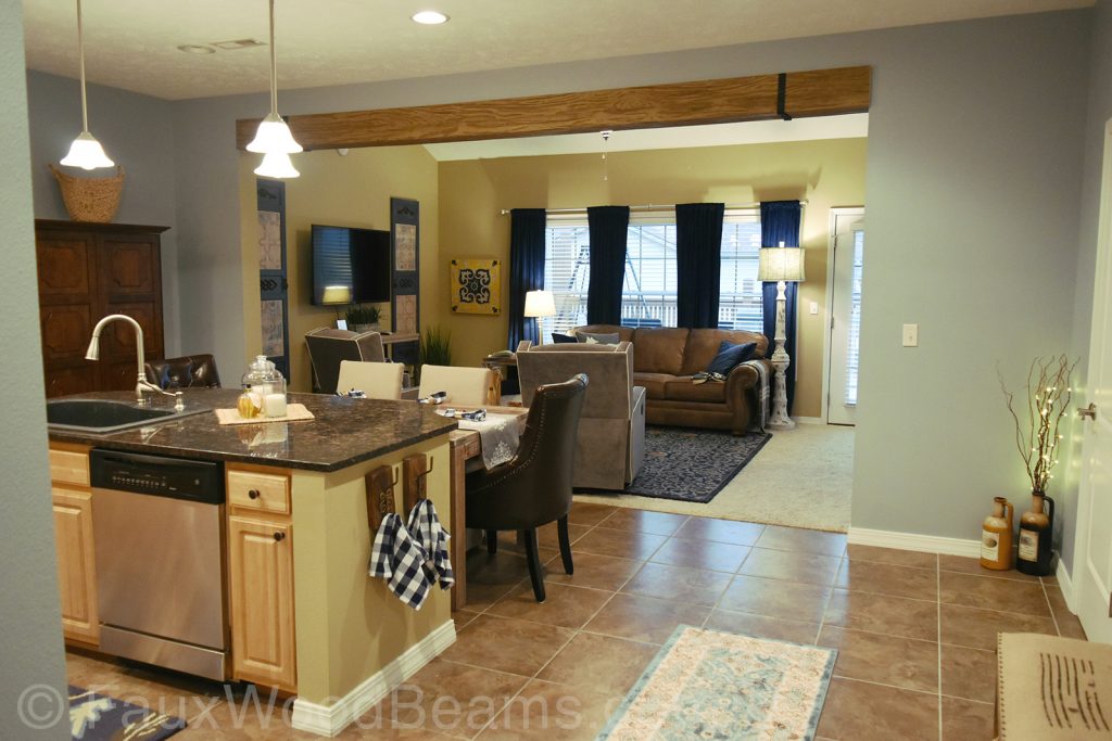 Cased opening between a living room and kitchen trimmed with a single Heritage ceiling beam.