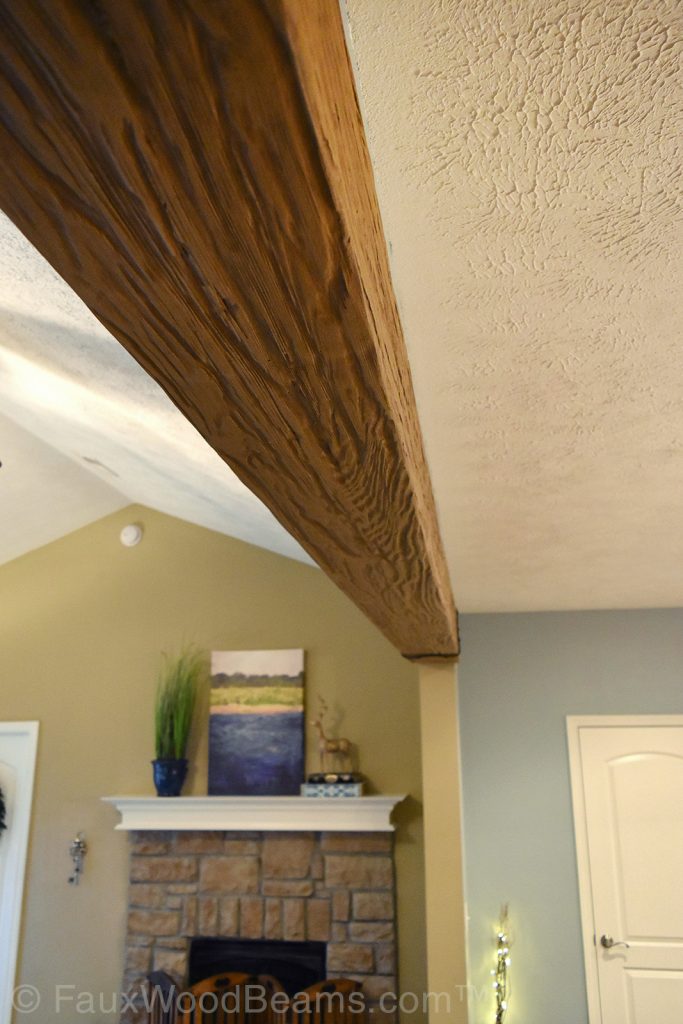 Close up view of a single Heritage beam in a Light Oak finish, separating a home's kitchen and living room.