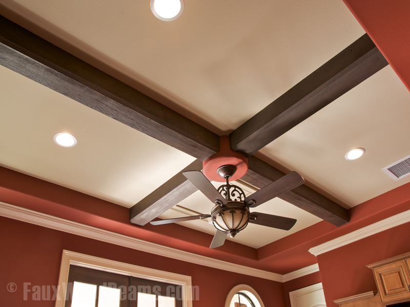 Ceiling fan with light installed in the cross section of two faux beams.