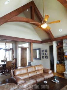 Living room ceiling framed with arched trusses and straight beams around the perimeter.