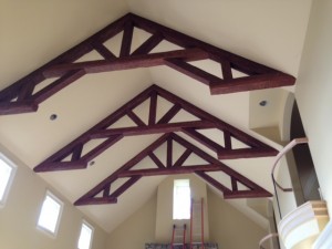 Ornate king post trusses made from faux wood installed on a cathedral ceiling.