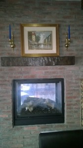 Both sides of this fireplace design look great with their new mantel shelves. Artificial wood mantel above a two sided gas fireplace with brick cladding.