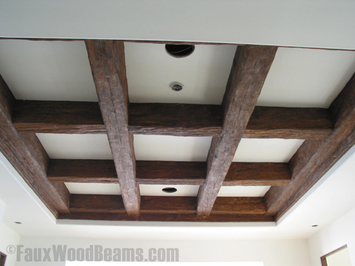 Tray ceiling with beams arranged in a coffered design, using beams with an authentic distressed wood look.