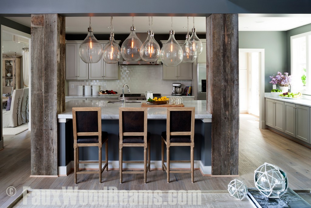 Weathered beams are converted into gorgeous pillars surrounding a kitchen island with overhanging lights.