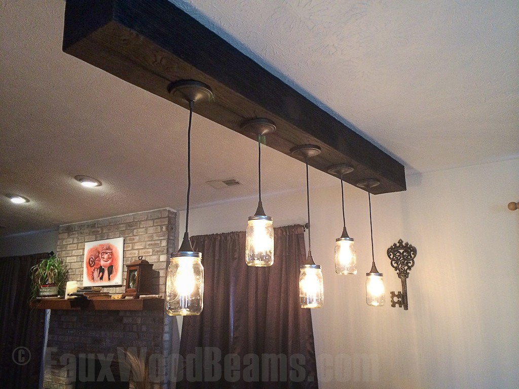 Vintage-style bell jar lights hung from a heavy sandblasted ceiling beam.