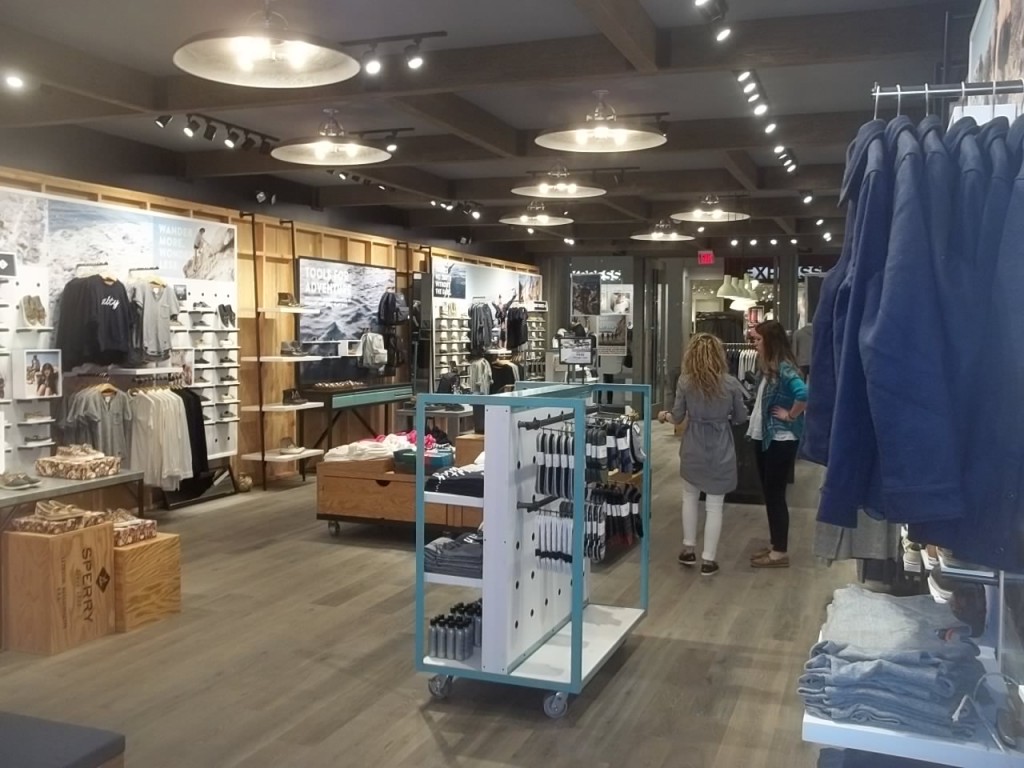 Hollow driftwood style beams nicely conceal ceiling ducts and cables in this Sperry outlet store.