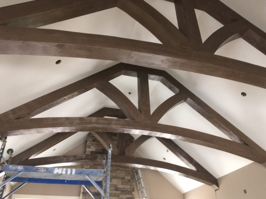 Cathedral ceiling trusses installed in a home's living room, built with straight and curved faux beams.