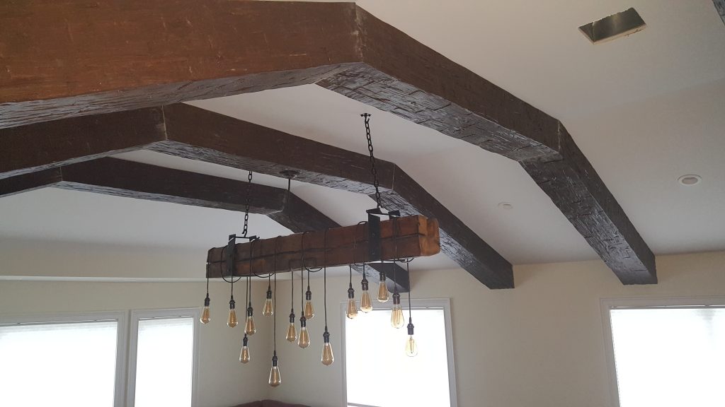 Wooden beam light fixture with power cable extending through the center of the hollow beam above.
