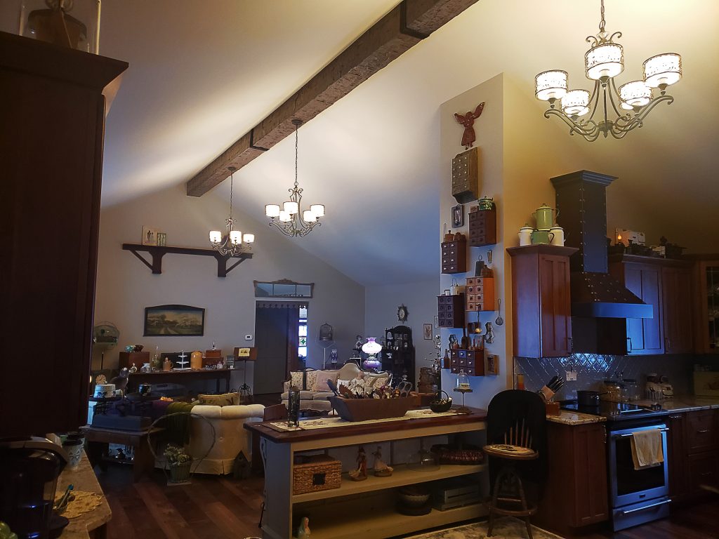 Custom Rough Hewn beams with beam straps installed in an open living room/kitchen.