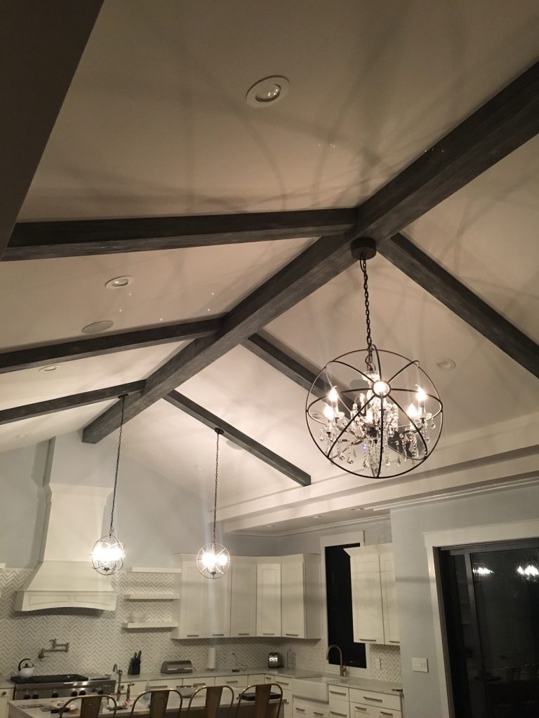 Hanging chandeliers from faux beams in a newly remodeled kitchen.