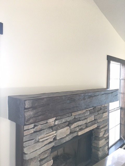 Custom Timber mantel installed on a stone fireplace in a Early American style home.