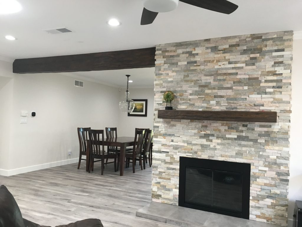 Open plan living room with dividing Custom Timber beam and matching fireplace mantel.