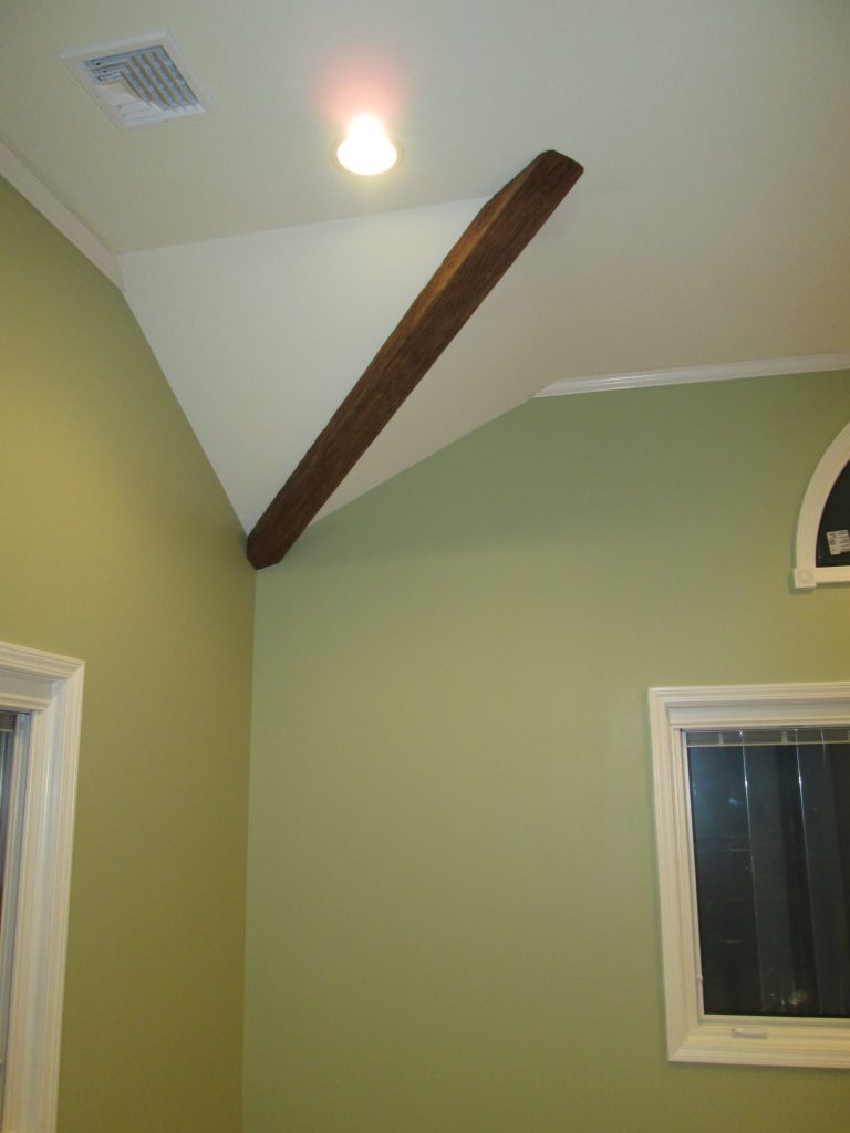 Attractive ceiling accent created by covering a plain white structural beam with faux sandblasted wood