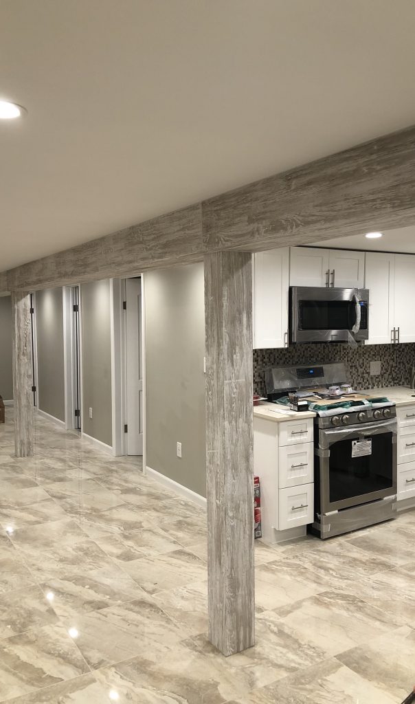 Finished basement with supports covered in Custom Driftwood that matches the modern design aesthetic.