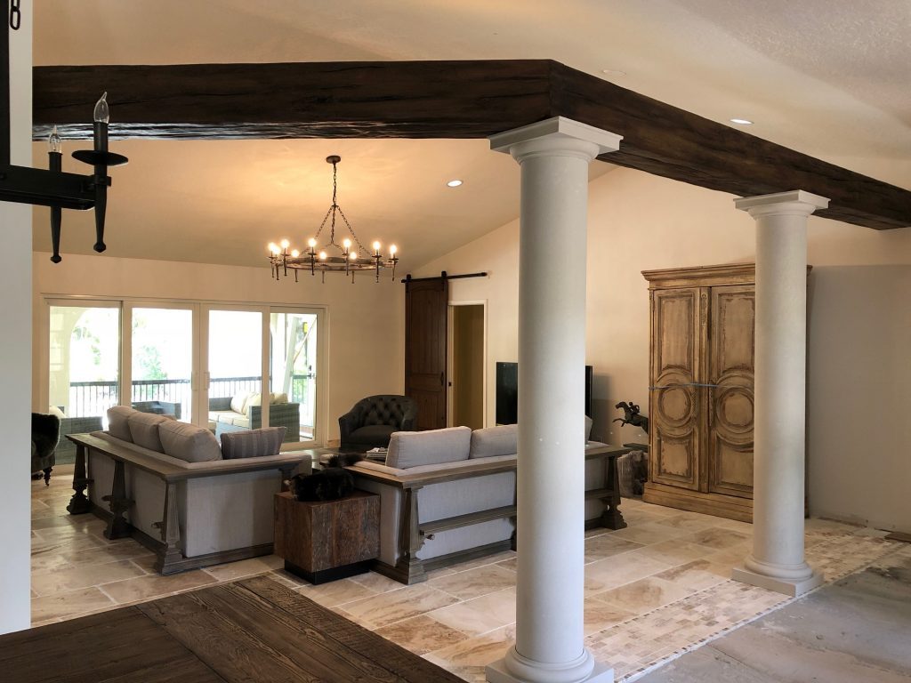 Living room with beams suspended from large white support columns to divide the space.